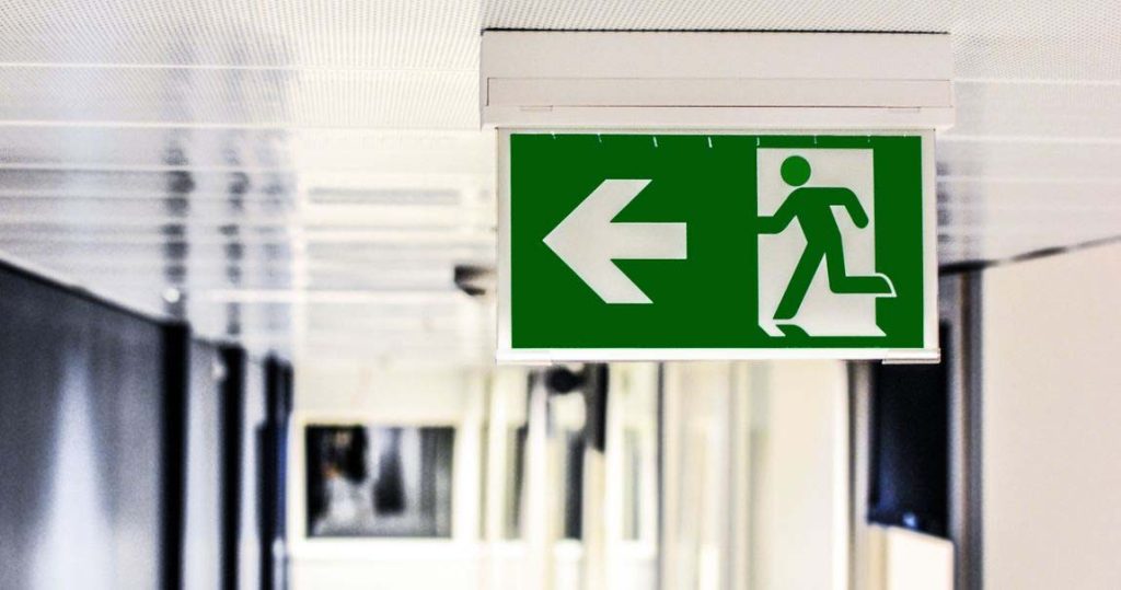 Fire Factory LED exit light displaying a left evacuation arrow inside a commercial building in Australia