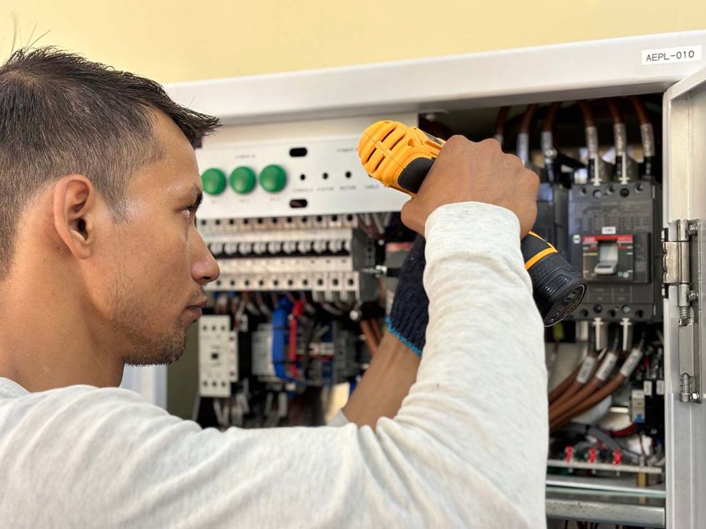 Technician installing and ensuring the cables and electrical connections inside a commercial fire alarm control panel supplied by Fire Factory in Australia.